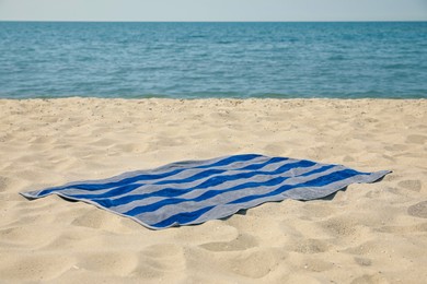 Photo of Striped beach towel on sand near sea