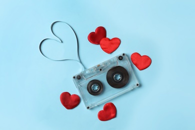 Photo of Music cassette and red hearts on light blue background, flat lay. Listening love song