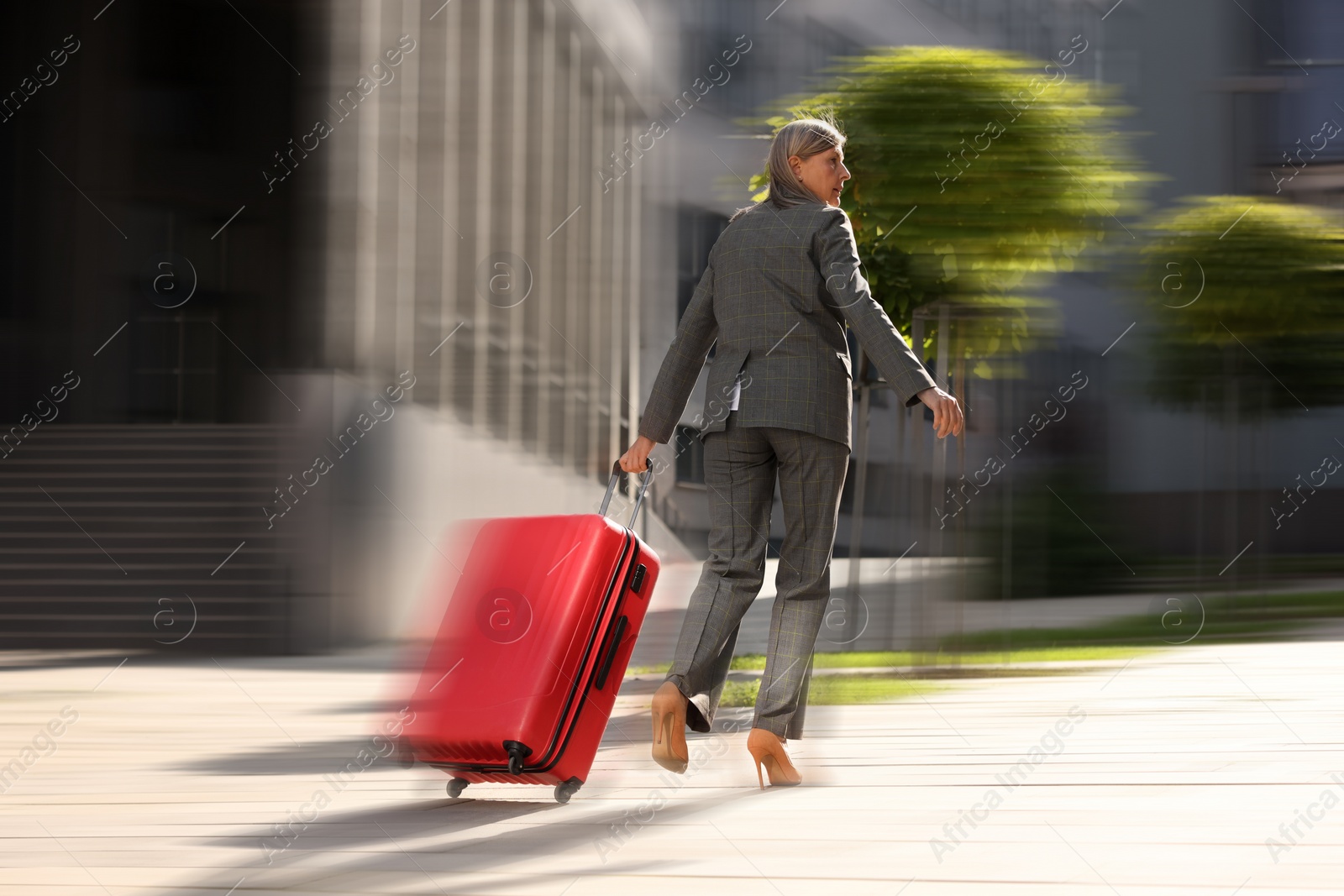 Image of Being late. Woman with suitcase running on city street. Motion blur effect