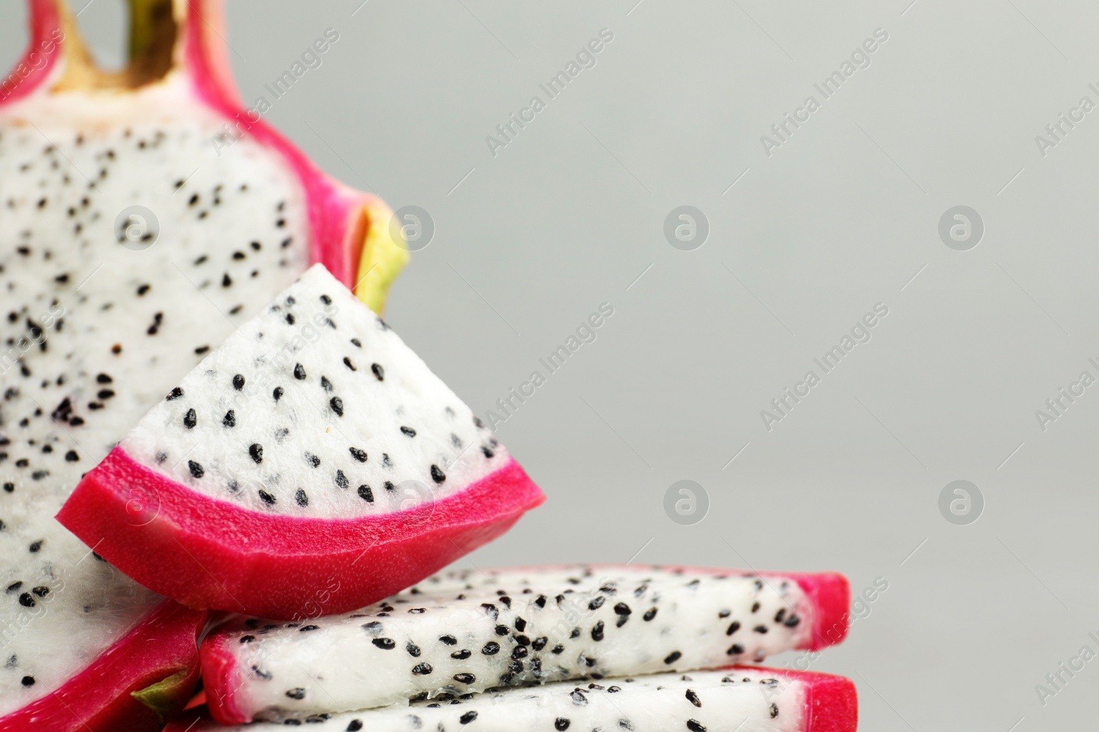 Photo of Delicious cut dragon fruit (pitahaya) on grey background, closeup. Space for text