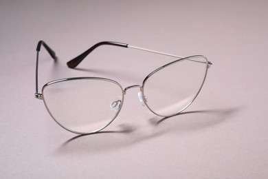 Stylish pair of glasses with metal frame on light background, closeup