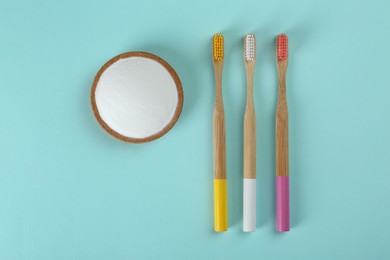 Bamboo toothbrushes and bowl of baking soda on turquoise background, flat lay