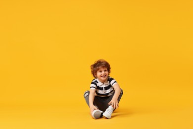 Photo of Happy little boy dancing on yellow background. Space for text