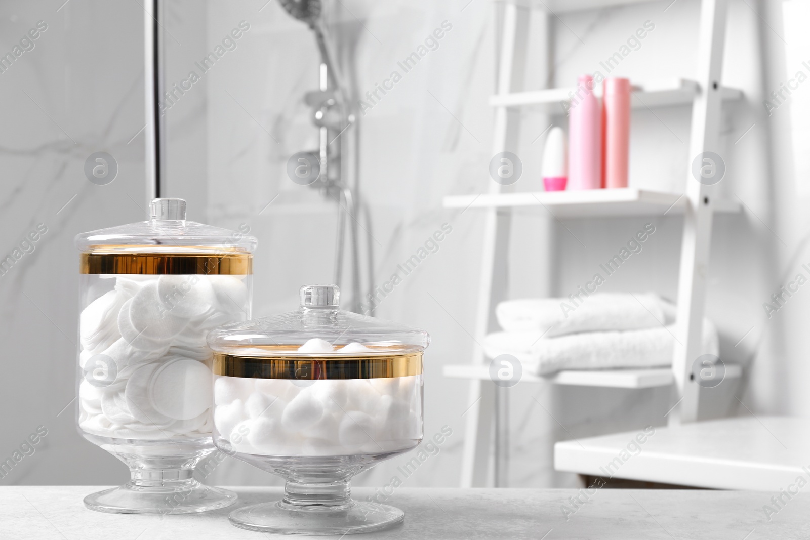 Photo of Cotton pads and balls on light grey table in bathroom