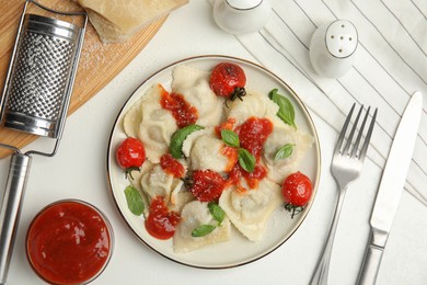 Photo of Tasty ravioli with tomato sauce served on white table, flat lay