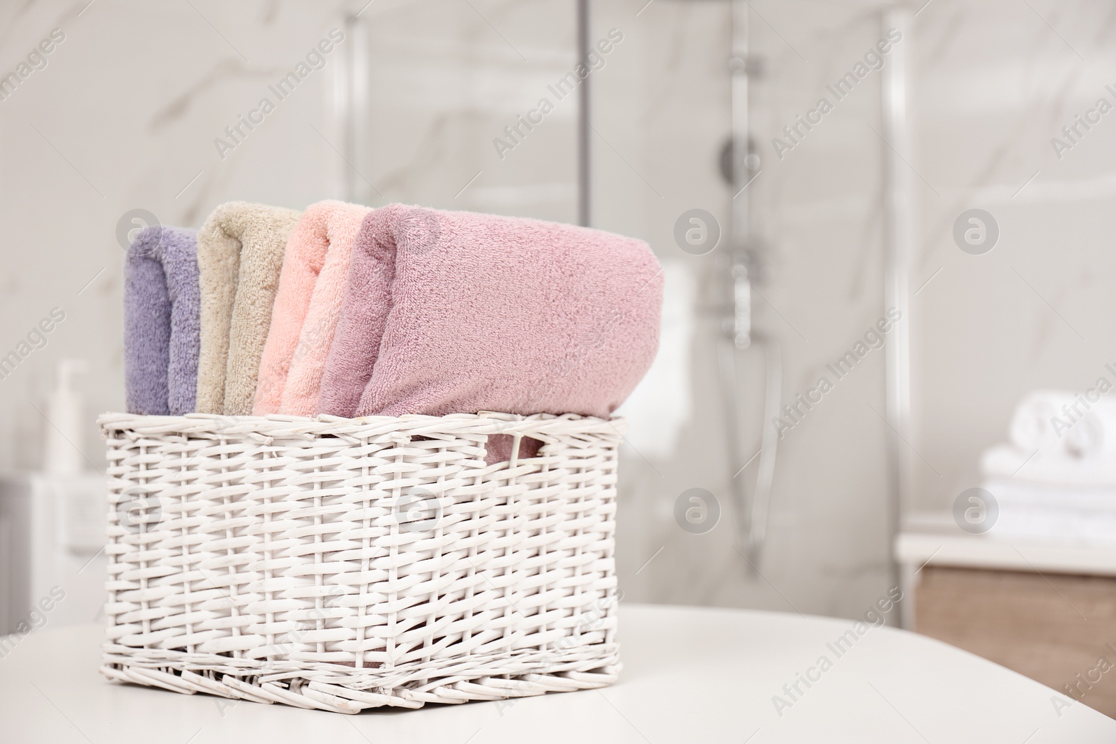 Photo of Basket with color towels on white table in bathroom. Space for text