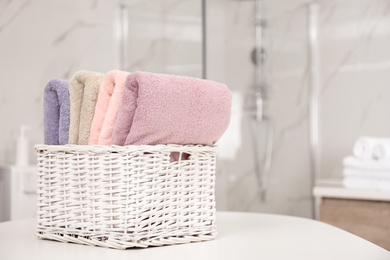 Photo of Basket with color towels on white table in bathroom. Space for text
