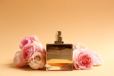 Photo of Bottle of perfume with beautiful roses on color background