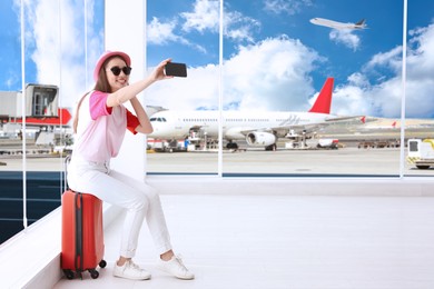 Image of Happy young woman taking selfie in airport