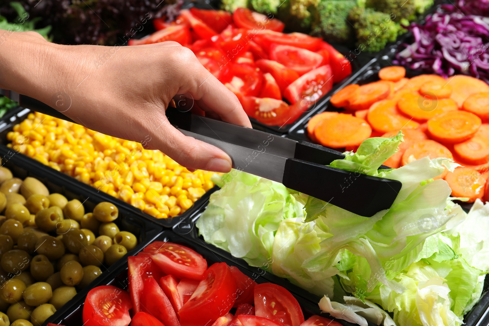 Photo of Young woman taking iceberg lettuce from salad bar, closeup