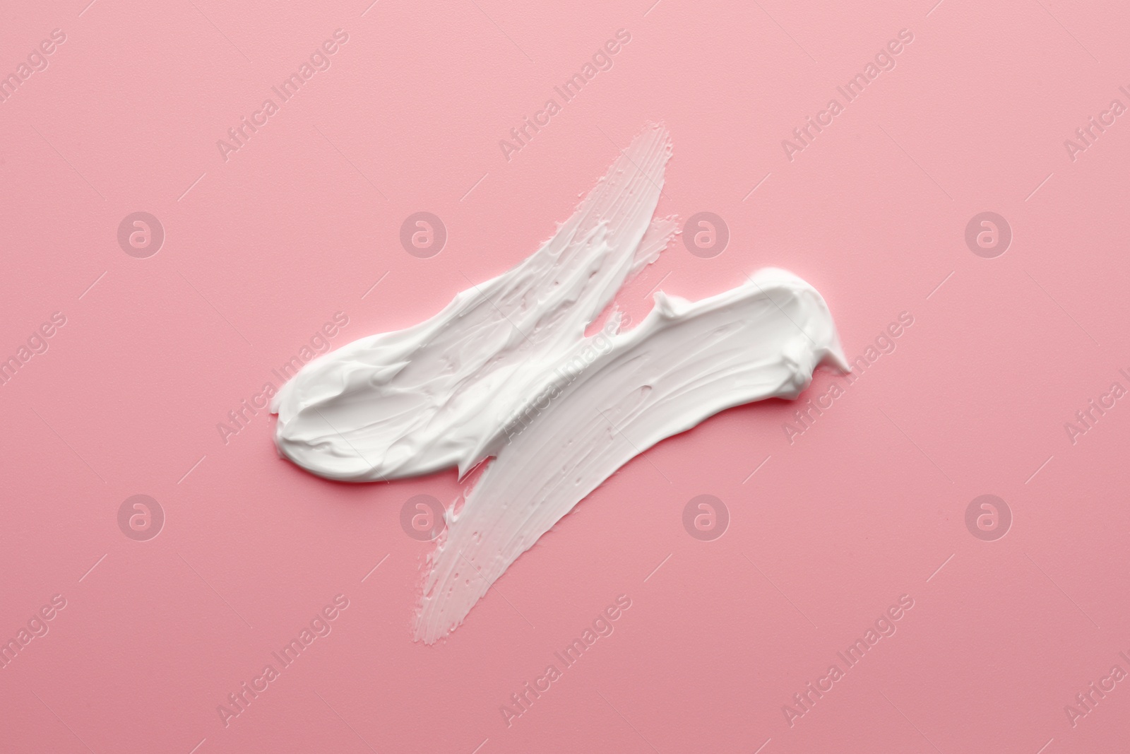 Photo of Sample facial cream on pink background, top view