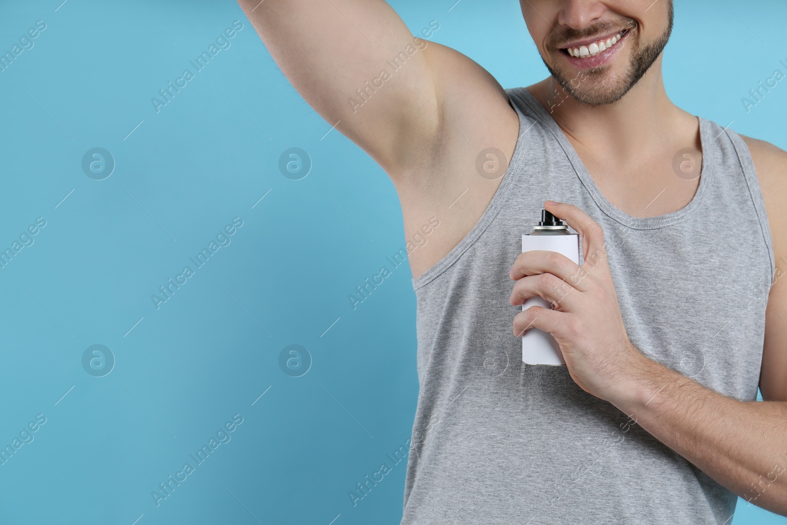 Photo of Man applying deodorant on turquoise background, closeup. Space for text