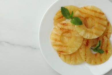 Tasty grilled pineapple slices with mint on white table, top view. Space for text