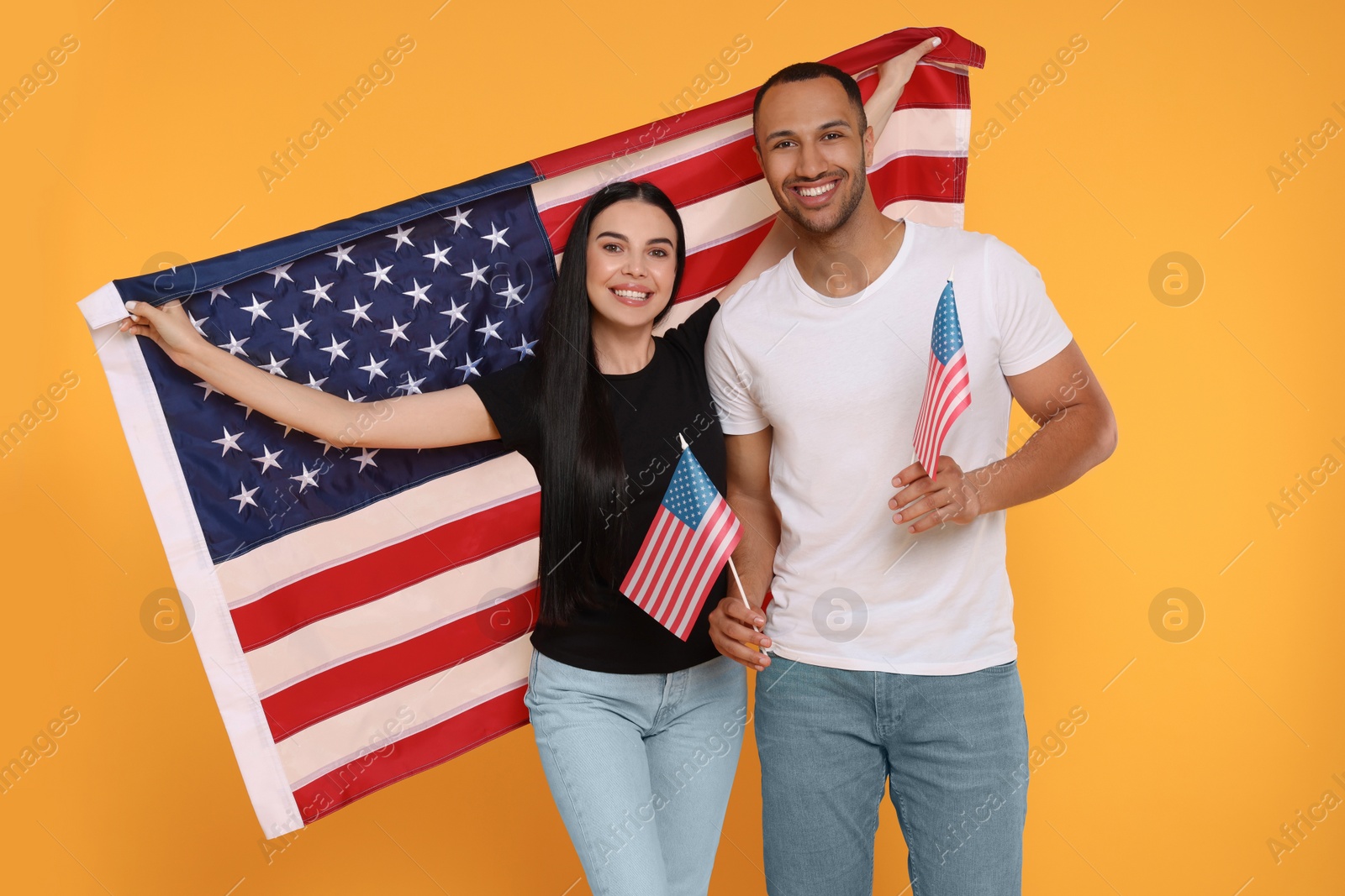 Photo of 4th of July - Independence Day of USA. Happy couple with American flags on yellow background