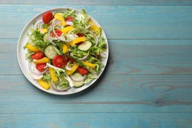 Photo of Tasty fresh vegetarian salad on light blue wooden table, top view. Space for text