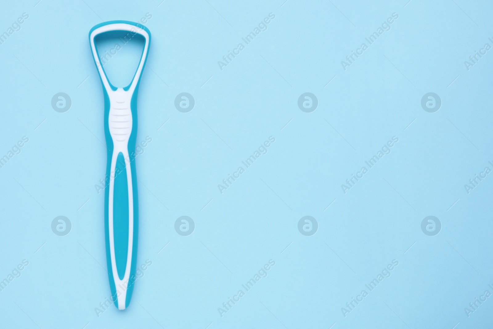 Photo of Tongue cleaner on light blue background, top view. Space for text