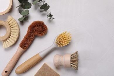 Photo of Cleaning brushes, baking soda, soap bar and eucalyptus on white table, flat lay. Space for text