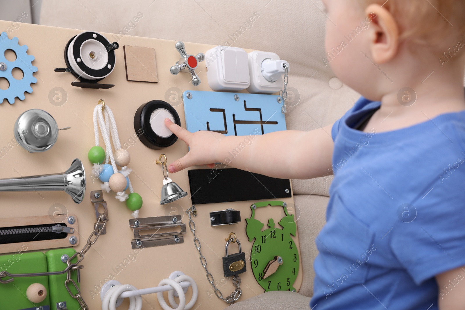 Photo of Cute little boy playing with busy board on sofa, closeup