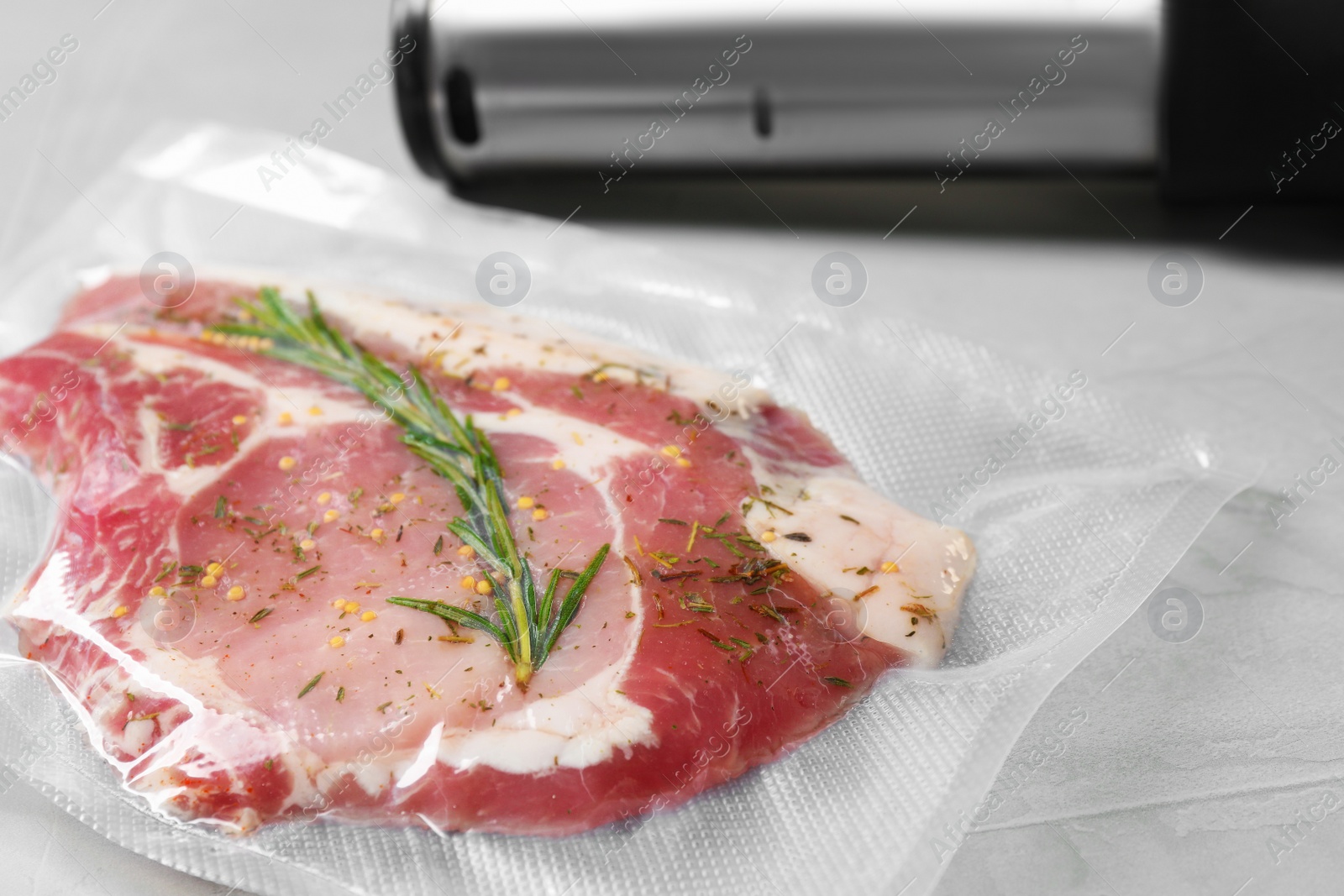 Photo of Sealer for vacuum packing with plastic bag of meat on light grey table, closeup