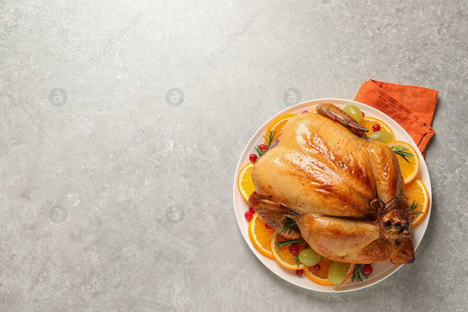 Photo of Platter of cooked turkey with garnish on grey background, top view. Space for text