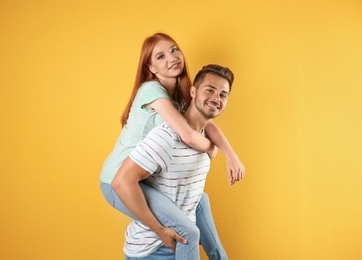 Young couple in stylish jeans on color background