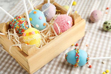 Delicious sweet cake pops in wooden crate on table, closeup. Easter holiday