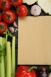 Blank recipe book and different ingredients on black wooden table, flat lay. Space for text