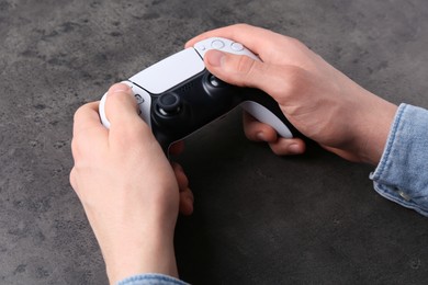 Photo of Man using wireless game controller at grey table, closeup