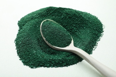 Photo of Spoon with spirulina algae powder on white background