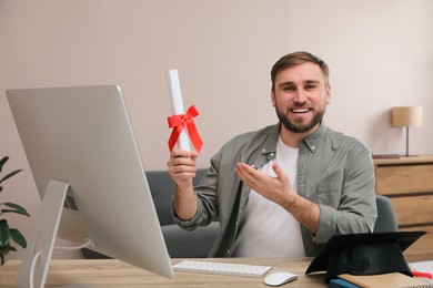 Photo of Happy student with graduation hat and diploma at workplace in office