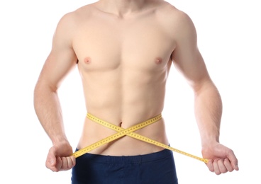 Photo of Young man with measuring tape showing his slim body on white background, closeup