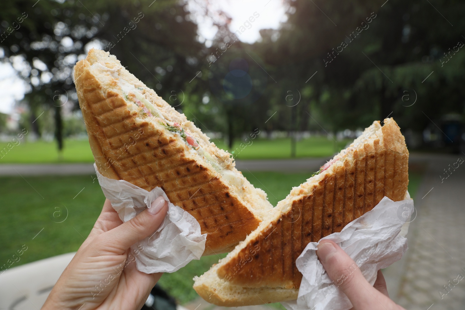 Photo of Man and woman holding delicious sandwiches outdoors, closeup. Street food