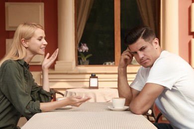 Photo of Man having boring date with talkative woman in outdoor cafe