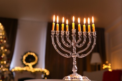 Photo of Silver menorah in room with Christmas decorations, space for text. Hanukkah symbol