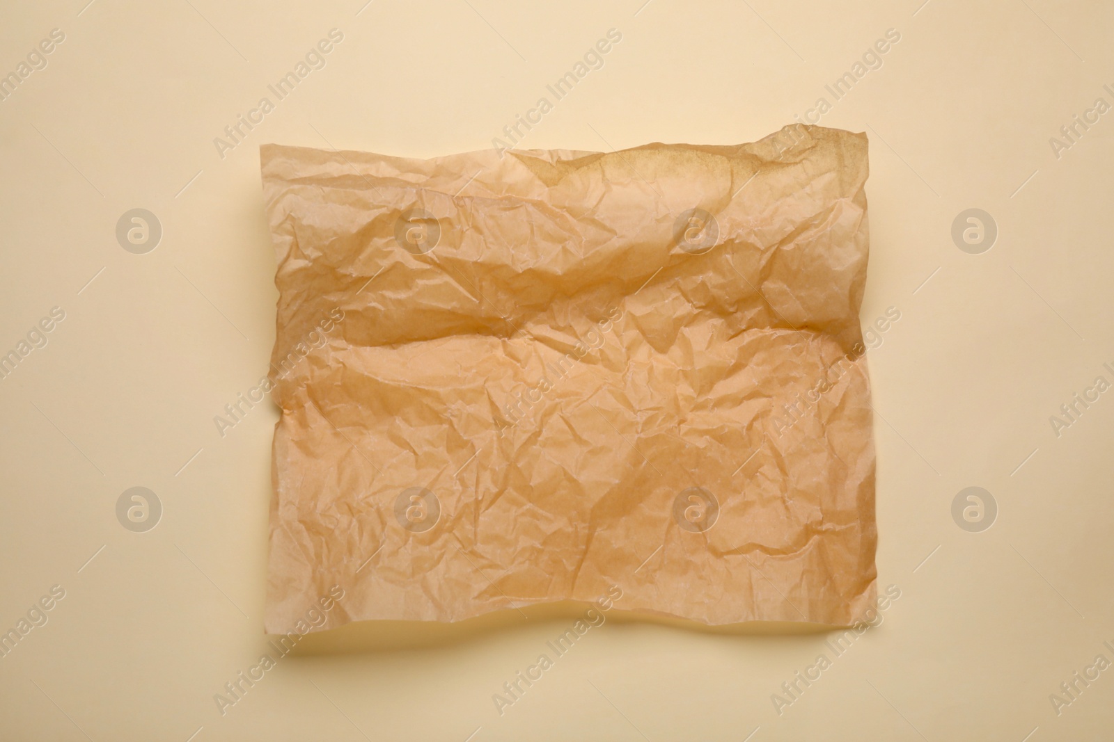 Photo of Sheet of crumpled baking paper on beige background, top view