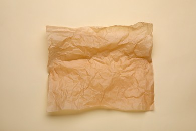 Photo of Sheet of crumpled baking paper on beige background, top view