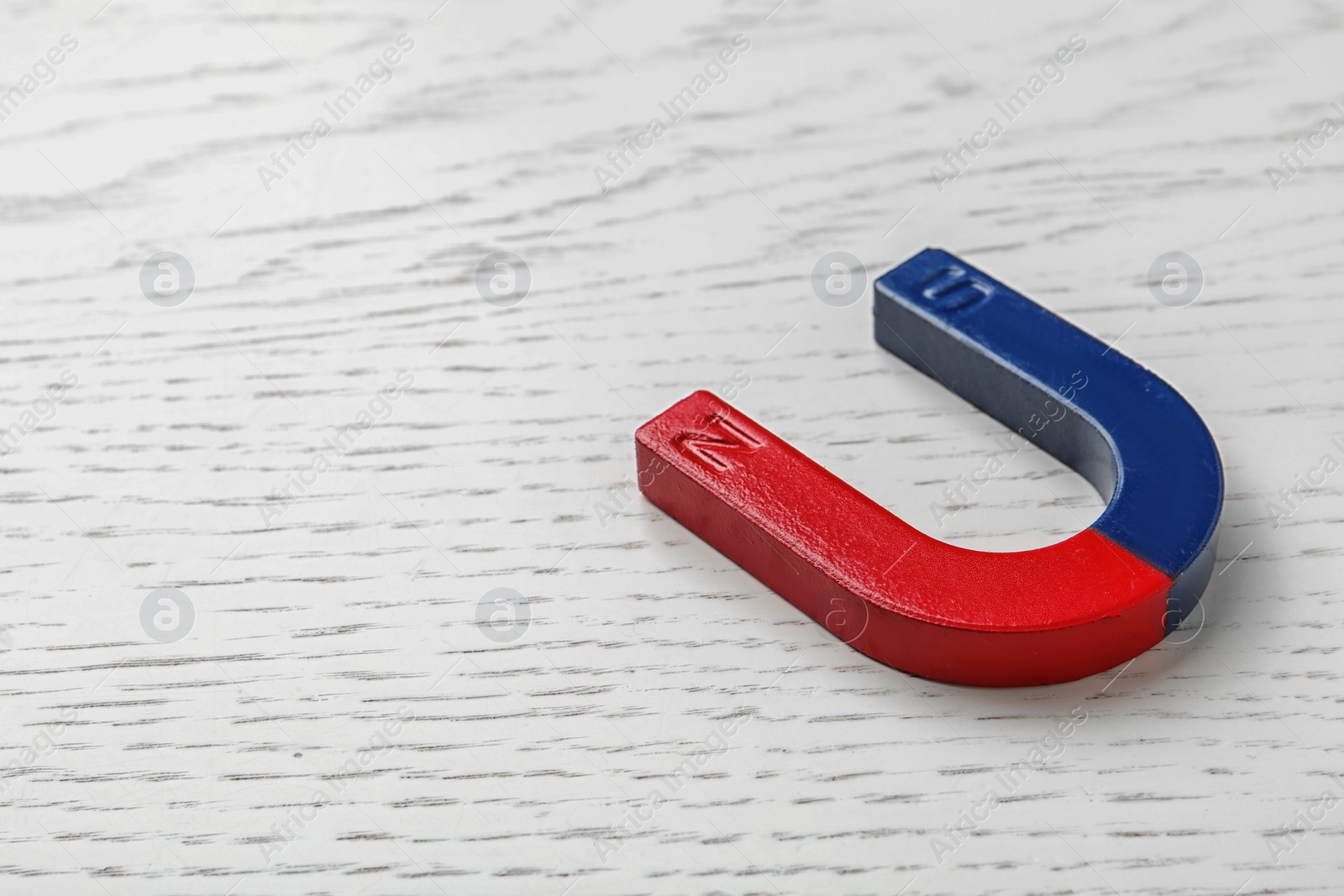 Photo of Red and blue horseshoe magnet on wooden background. Space for text