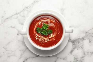 Dish with fresh homemade tomato soup on marble background, top view