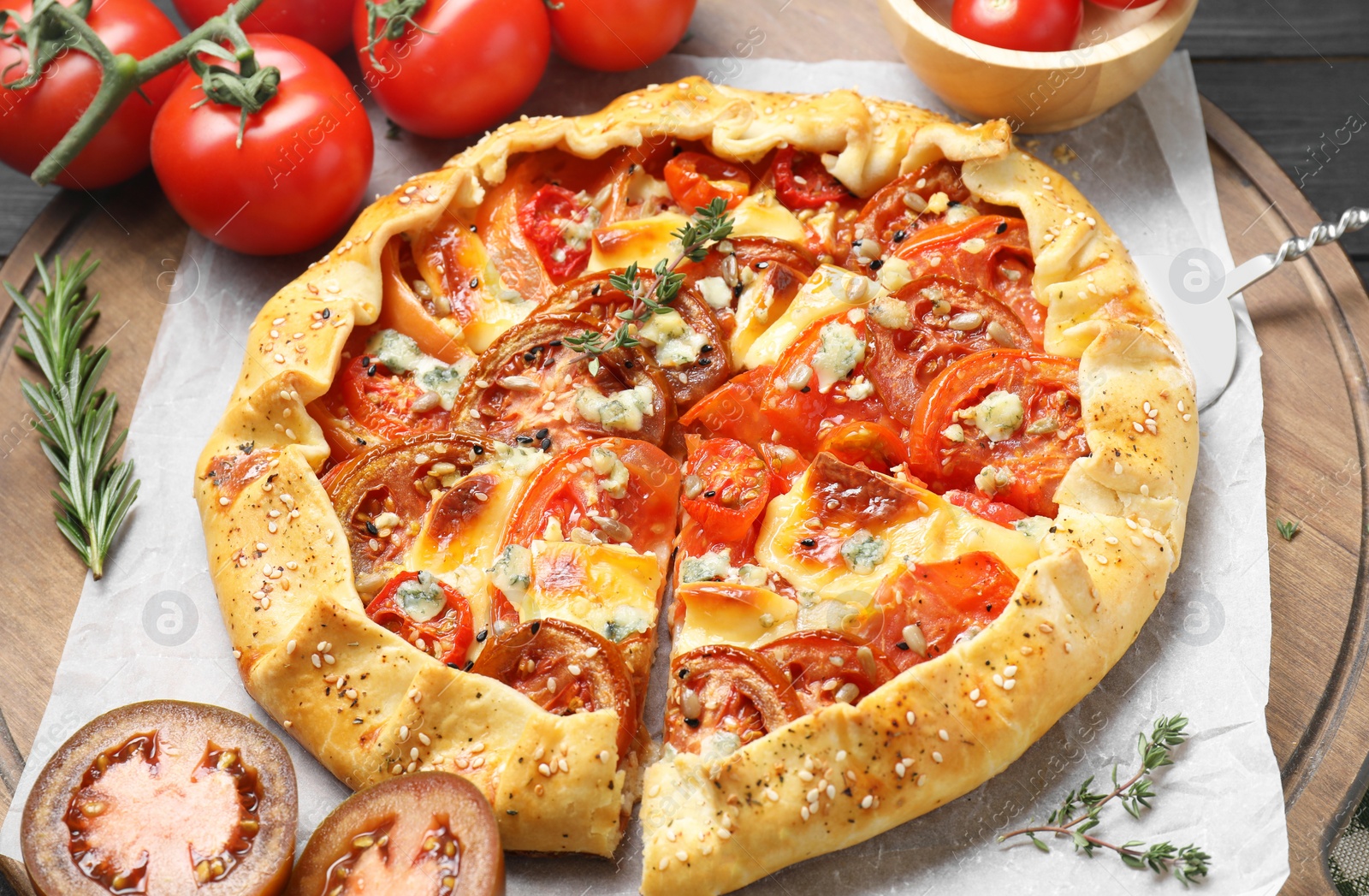 Photo of Tasty galette with tomato and cheese (Caprese galette) on wooden board, closeup