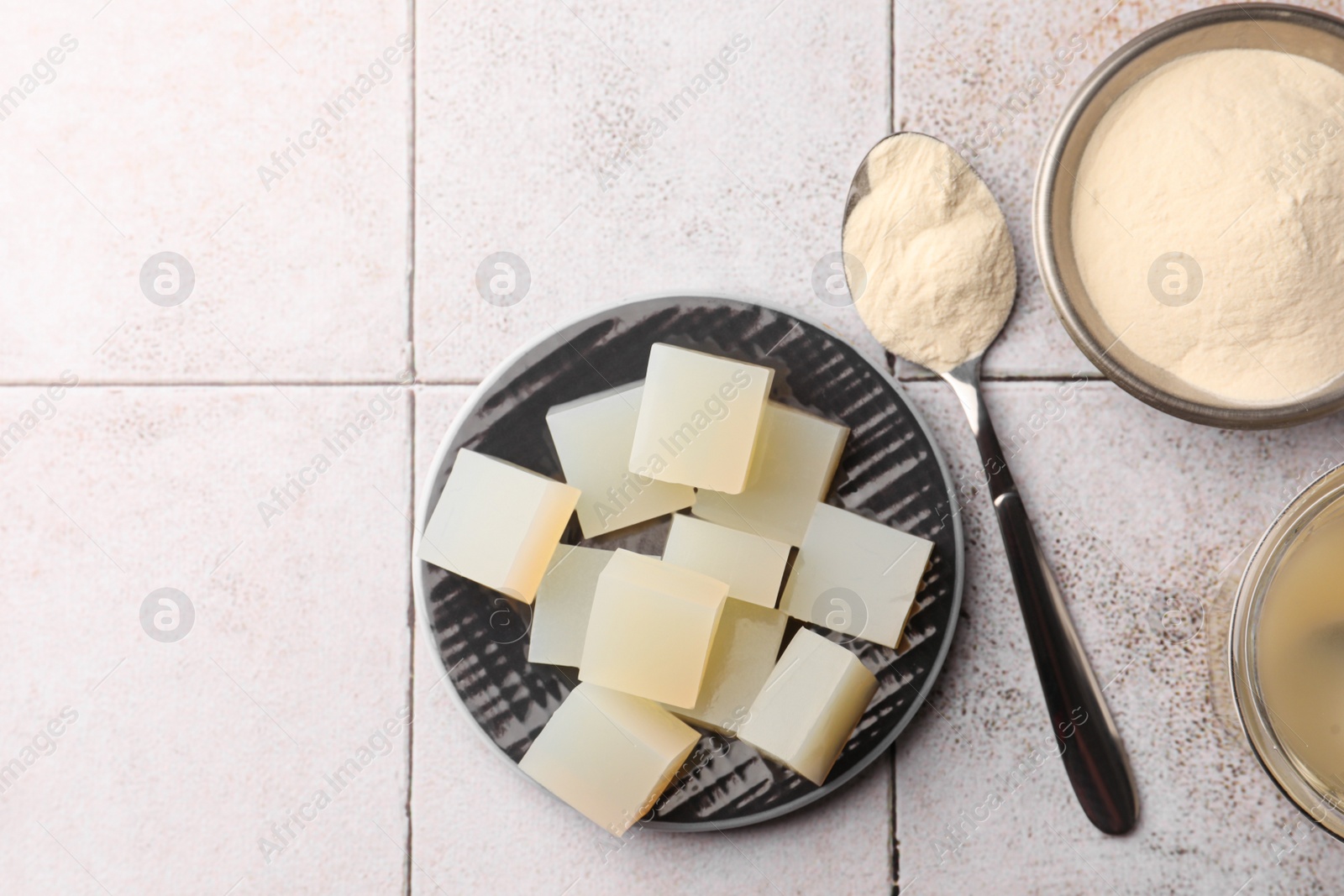 Photo of Agar-agar jelly cubes and powder on tiled surface, flat lay. Space for text