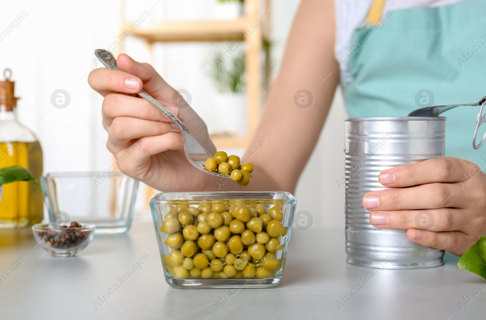 Photo of Young woman with canned green peas at table