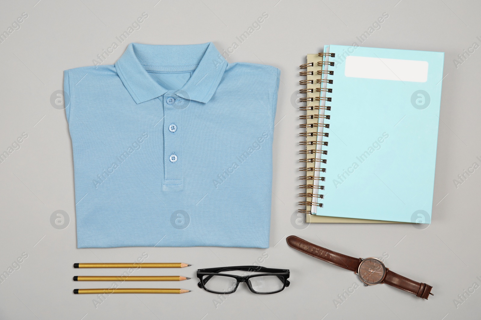 Photo of Blue shirt and stationery on grey background, top view. School uniform