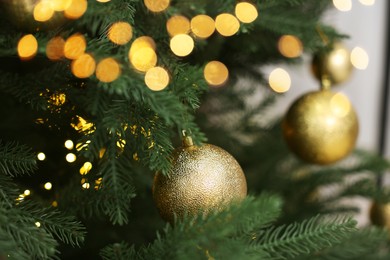 Photo of Christmas balls hanging on fir tree indoors, closeup