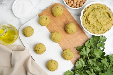 Photo of Raw falafel balls and ingredients on white marble table, flat lay