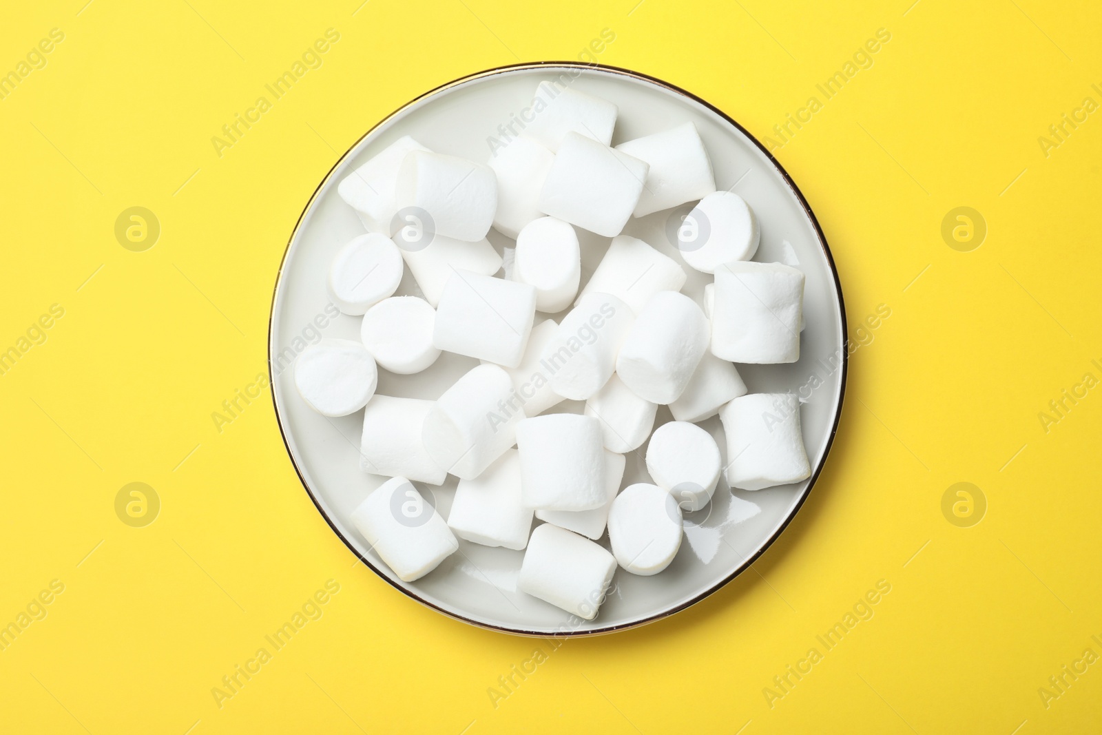 Photo of Delicious puffy marshmallows on yellow background, top view