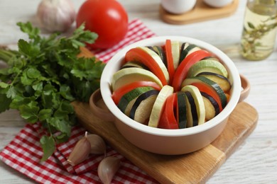 Cooking delicious ratatouille. Dish with different cut vegetables on white wooden table, closeup