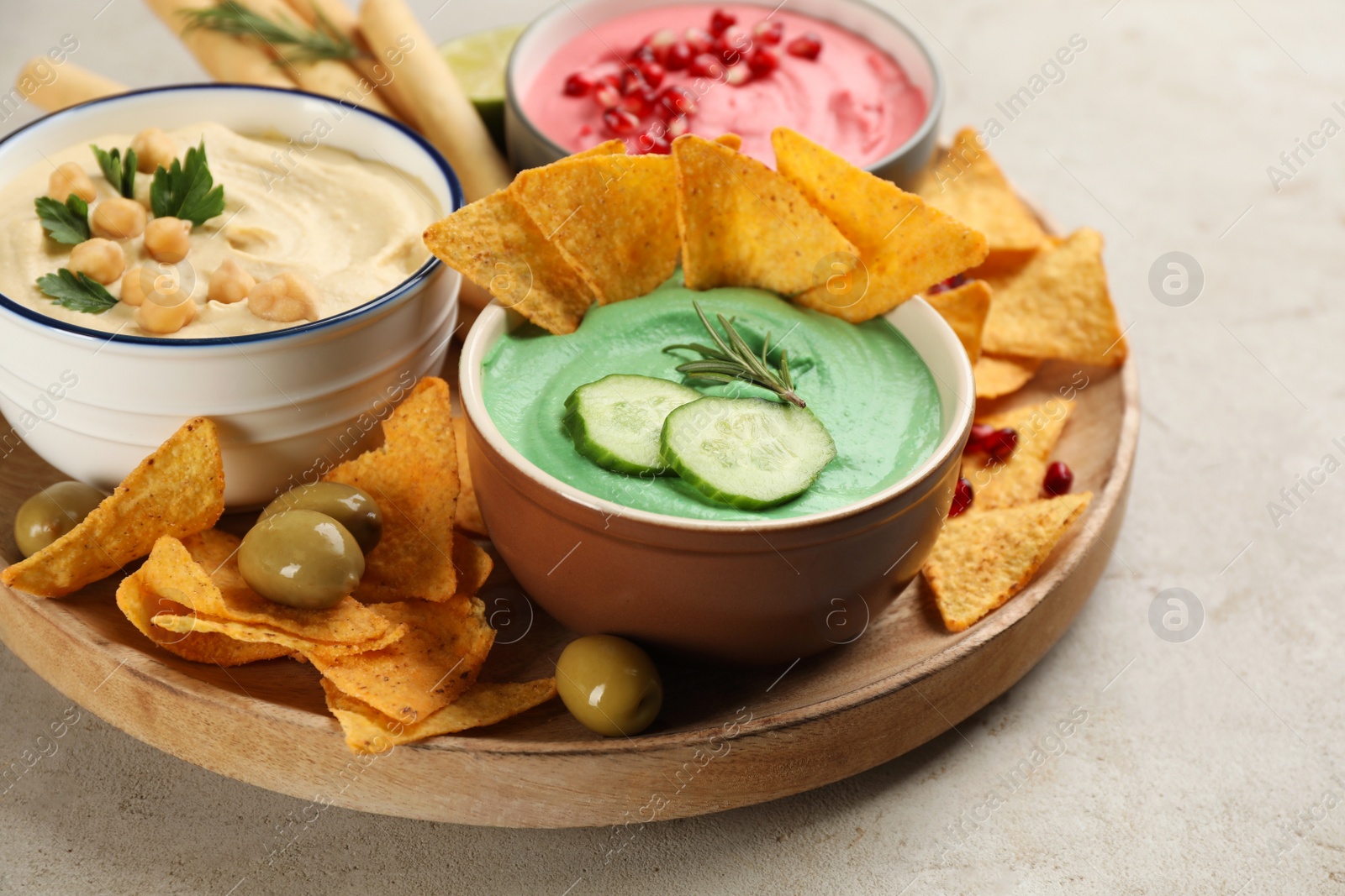 Photo of Different kinds of tasty hummus served with snacks on light table