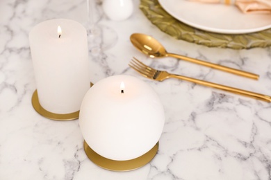 Burning candles on served white marble table