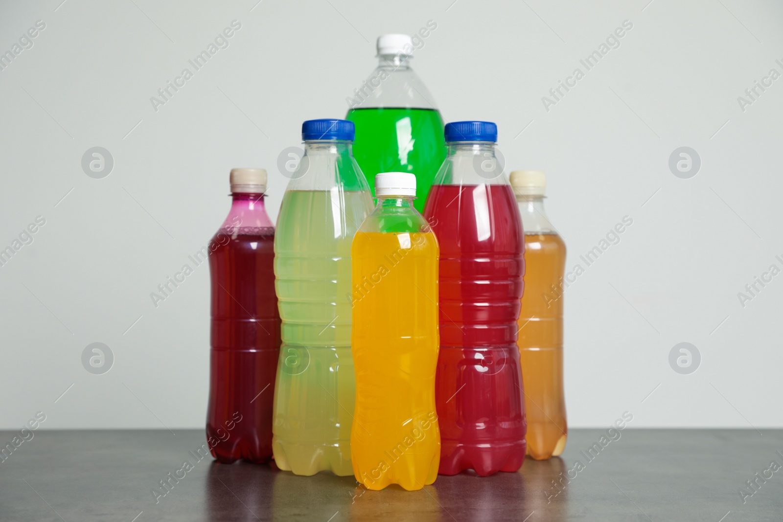 Photo of Bottles of soft drinks on table against grey background