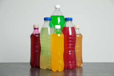 Photo of Bottles of soft drinks on table against grey background